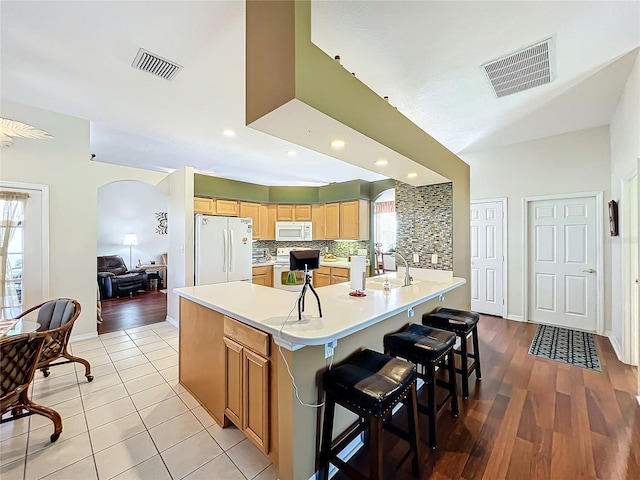 kitchen featuring a kitchen island with sink, light hardwood / wood-style flooring, white appliances, and plenty of natural light