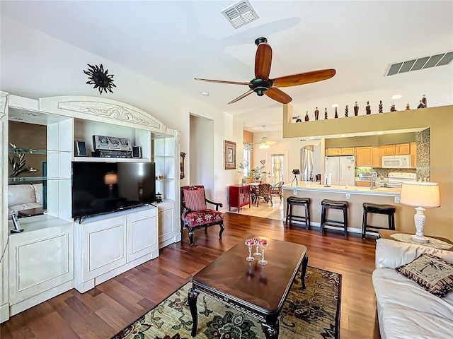 living room featuring dark wood-type flooring, ceiling fan, and sink