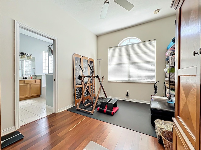 exercise area with ceiling fan and light wood-type flooring