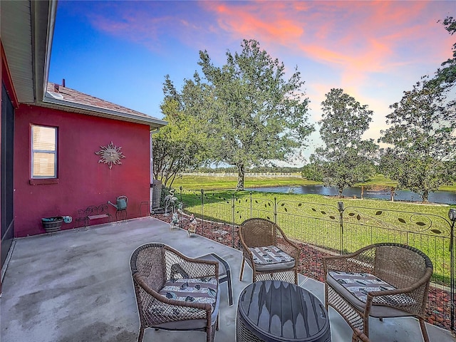 patio terrace at dusk with a lawn and a water view