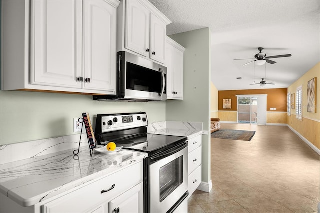 kitchen with appliances with stainless steel finishes, white cabinetry, light stone countertops, and a textured ceiling