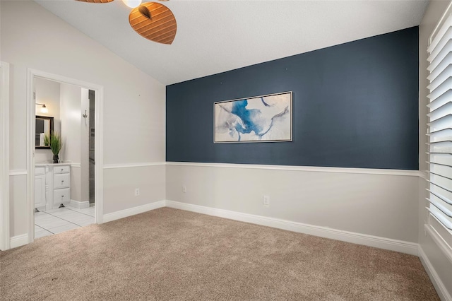 unfurnished bedroom with ensuite bath, vaulted ceiling, and light colored carpet