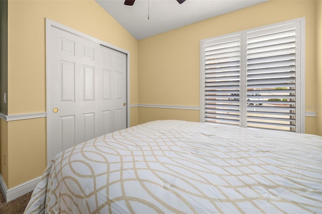 bedroom featuring a closet, carpet, vaulted ceiling, a textured ceiling, and ceiling fan