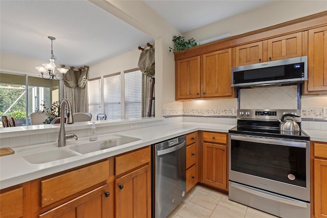 kitchen with a chandelier, appliances with stainless steel finishes, decorative backsplash, and sink