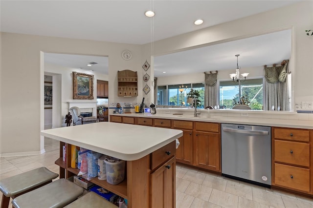 kitchen with pendant lighting, sink, stainless steel dishwasher, a kitchen island, and a chandelier