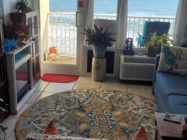 interior space with a view of the beach, a healthy amount of sunlight, a water view, and light tile patterned floors