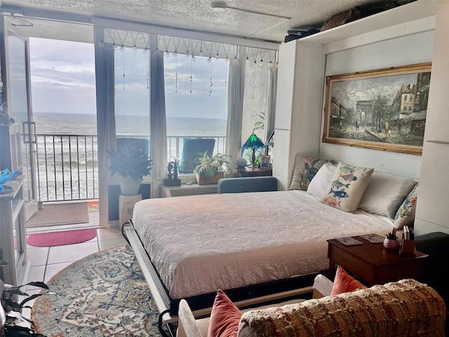 bedroom with a textured ceiling, a water view, light tile patterned flooring, and floor to ceiling windows