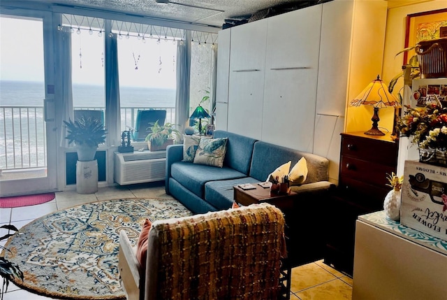 living area featuring a water view, a wealth of natural light, a textured ceiling, and light tile patterned floors