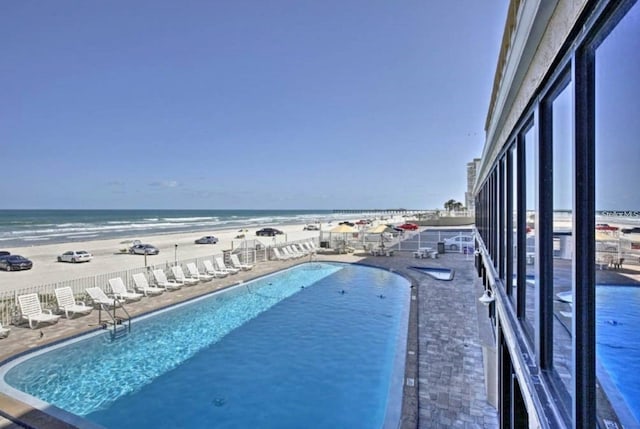 pool featuring a view of the beach, a patio, and a water view