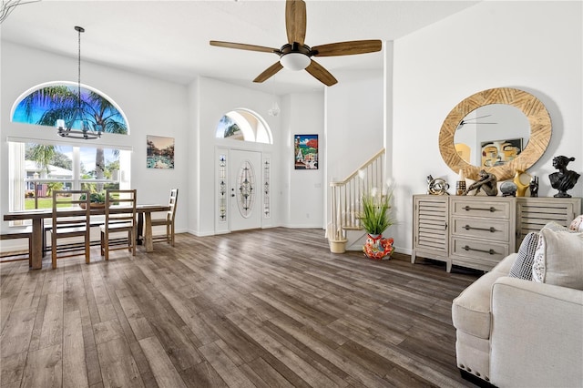 foyer entrance with a towering ceiling, dark hardwood / wood-style floors, and ceiling fan with notable chandelier