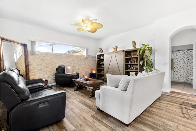 living room featuring a barn door, wood-type flooring, and ceiling fan