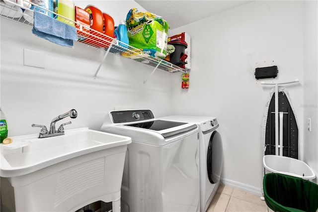 clothes washing area with sink, light tile patterned flooring, and washer and clothes dryer