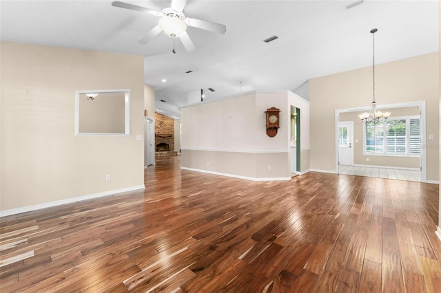 unfurnished living room featuring hardwood / wood-style flooring, ceiling fan with notable chandelier, and a stone fireplace