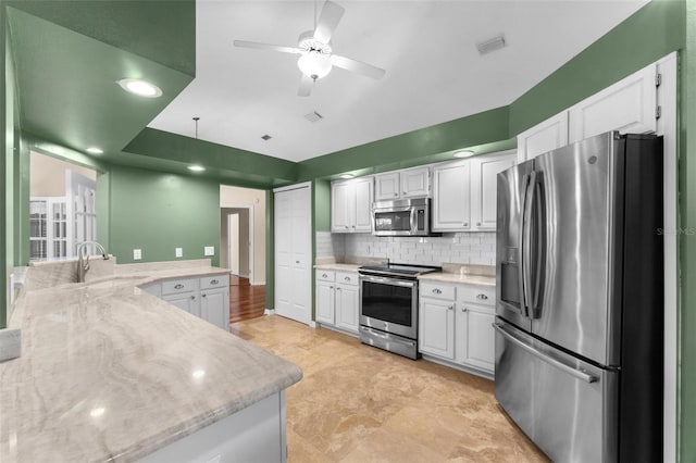 kitchen with backsplash, sink, white cabinets, appliances with stainless steel finishes, and ceiling fan