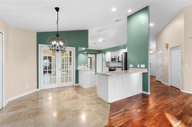 kitchen featuring appliances with stainless steel finishes, light wood-type flooring, backsplash, kitchen peninsula, and white cabinets