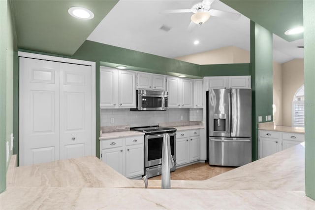 kitchen featuring lofted ceiling, tasteful backsplash, ceiling fan, appliances with stainless steel finishes, and white cabinetry