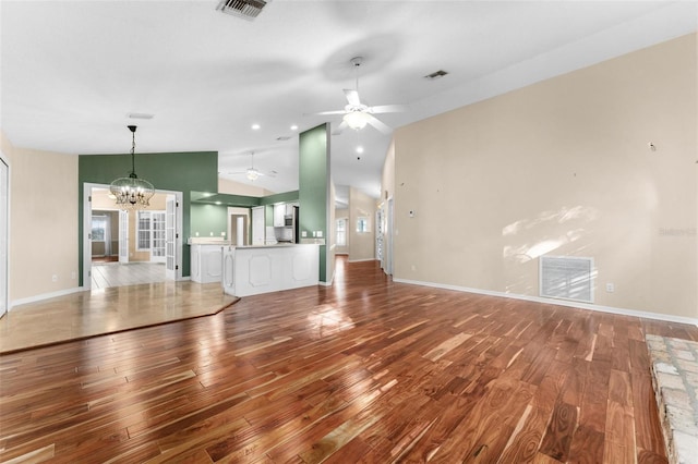 unfurnished living room with ceiling fan with notable chandelier, light wood-type flooring, and vaulted ceiling