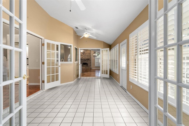 unfurnished sunroom with lofted ceiling, a brick fireplace, and ceiling fan