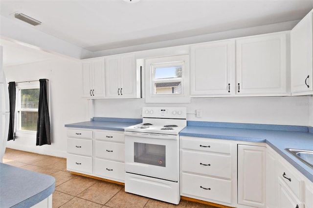 kitchen with white electric range oven, white cabinets, light tile patterned floors, and plenty of natural light