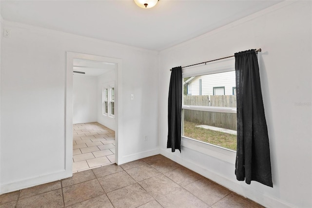 unfurnished room with ornamental molding and light tile patterned floors