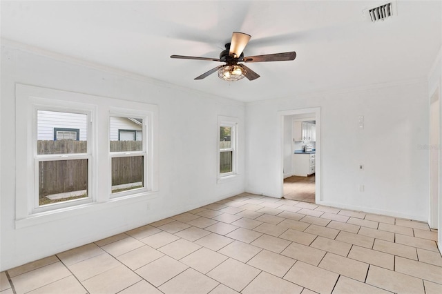 tiled empty room with crown molding, ceiling fan, and plenty of natural light