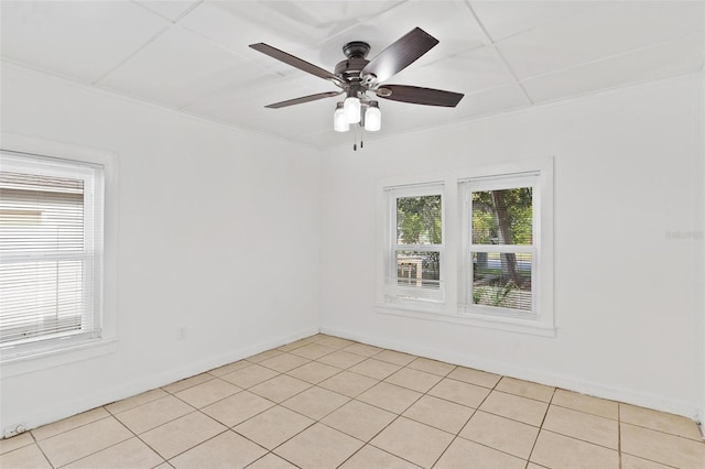 tiled spare room with crown molding, a paneled ceiling, and ceiling fan