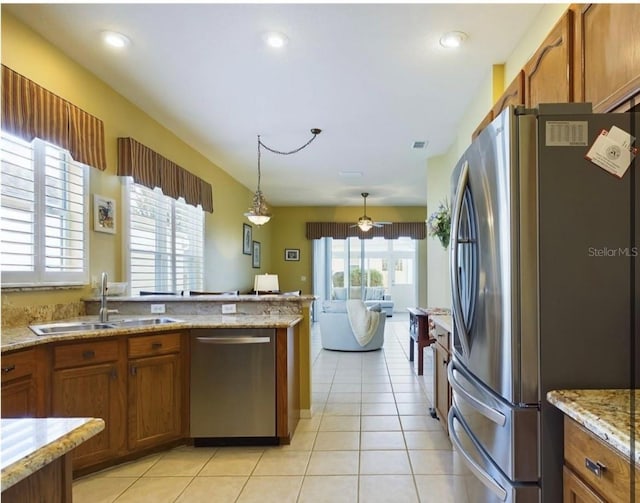 kitchen with sink, light stone counters, hanging light fixtures, light tile patterned floors, and stainless steel appliances