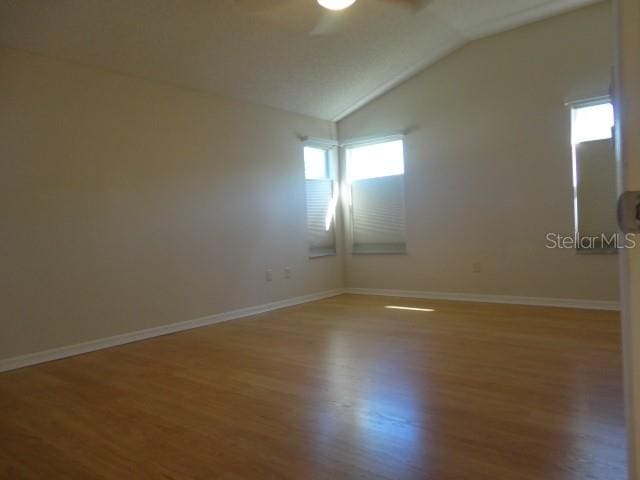 unfurnished room with ceiling fan, wood-type flooring, vaulted ceiling, and a wealth of natural light