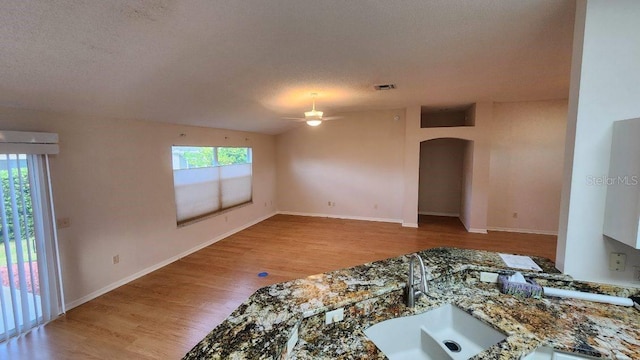 living room with ceiling fan, a textured ceiling, a wealth of natural light, and light wood-type flooring