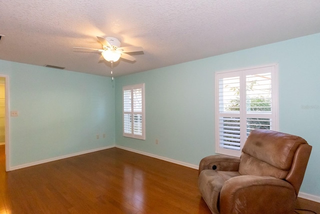 living area featuring ceiling fan, a textured ceiling, and dark hardwood / wood-style floors