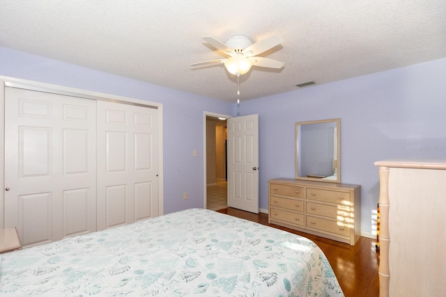 bedroom featuring a textured ceiling, dark wood-type flooring, ceiling fan, and a closet