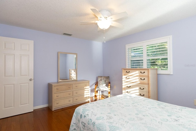 bedroom featuring dark hardwood / wood-style flooring, a textured ceiling, and ceiling fan