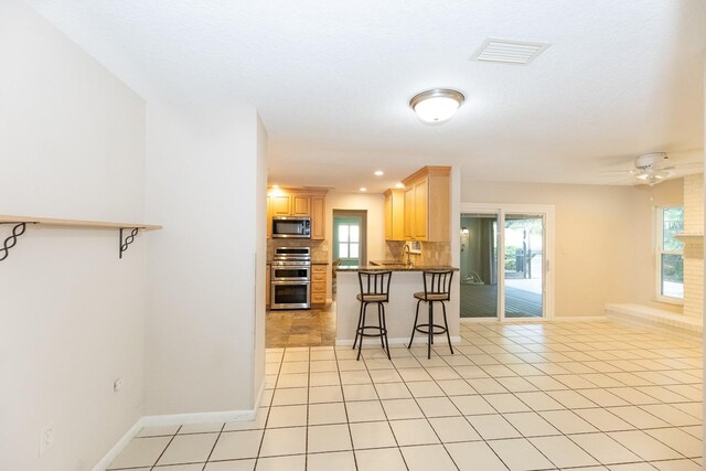 kitchen with kitchen peninsula, appliances with stainless steel finishes, a breakfast bar area, and plenty of natural light