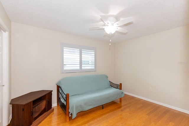 living area featuring ceiling fan, a textured ceiling, and light wood-type flooring