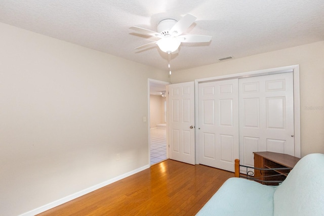 interior space featuring hardwood / wood-style floors, ceiling fan, and a textured ceiling