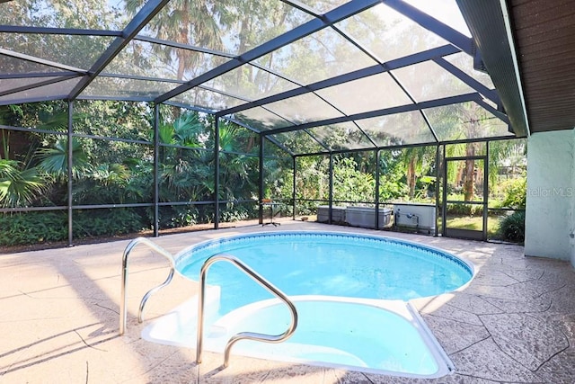 view of pool with glass enclosure and a patio area