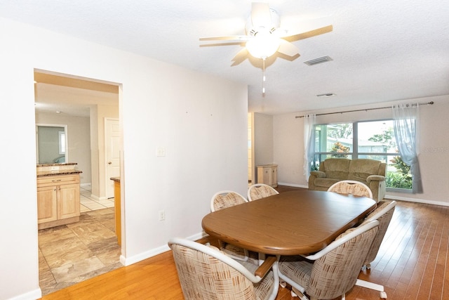 dining space with ceiling fan, a textured ceiling, and light hardwood / wood-style flooring