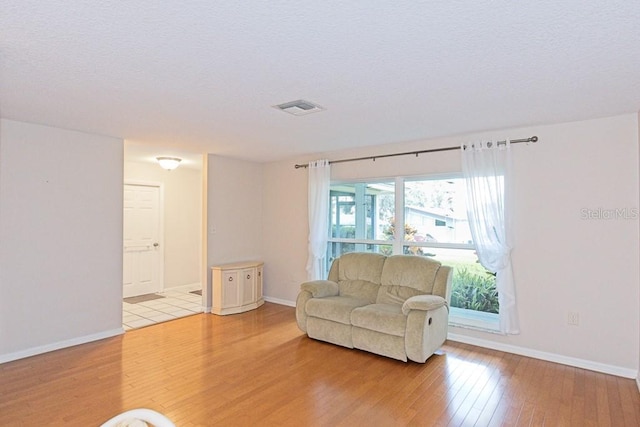 living area with a textured ceiling and light wood-type flooring