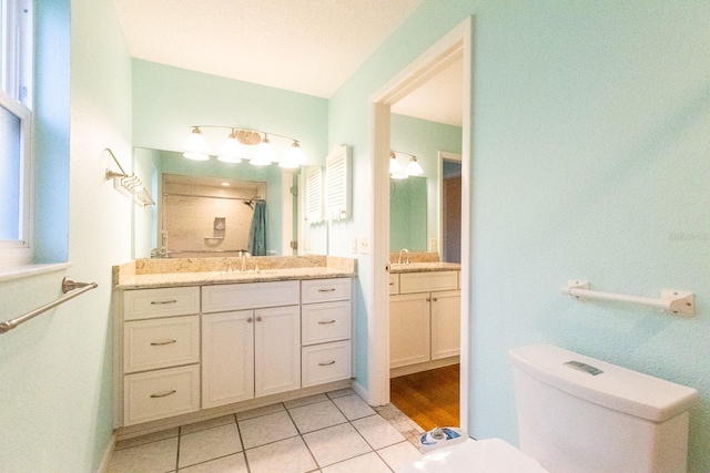 bathroom featuring toilet, vanity, tile patterned floors, and curtained shower