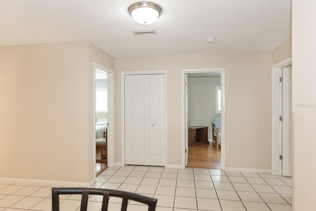 corridor featuring light tile patterned flooring and a textured ceiling