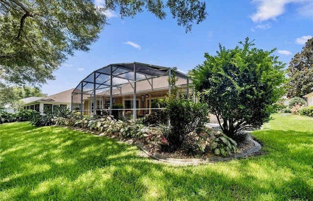 rear view of property with glass enclosure and a yard