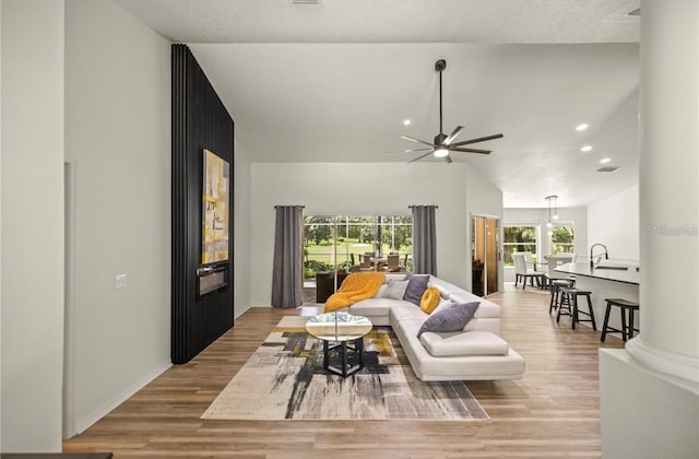 living room featuring decorative columns, ceiling fan, and light hardwood / wood-style flooring