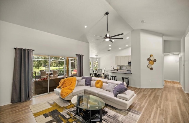 living room with high vaulted ceiling, ceiling fan, light wood-type flooring, and sink