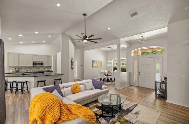 living room featuring high vaulted ceiling, light hardwood / wood-style flooring, ceiling fan, and sink