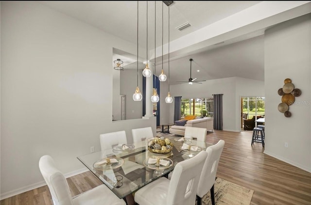 dining area featuring ceiling fan, wood-type flooring, and vaulted ceiling