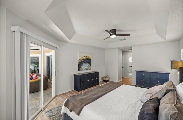 bedroom with a raised ceiling, ceiling fan, and light hardwood / wood-style flooring