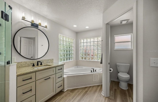 full bathroom featuring hardwood / wood-style flooring, a textured ceiling, vanity, shower with separate bathtub, and toilet