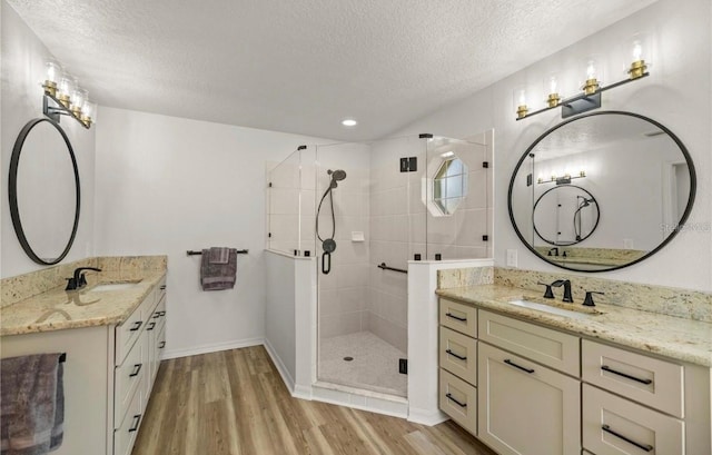 bathroom with hardwood / wood-style floors, a shower with door, a textured ceiling, and vanity