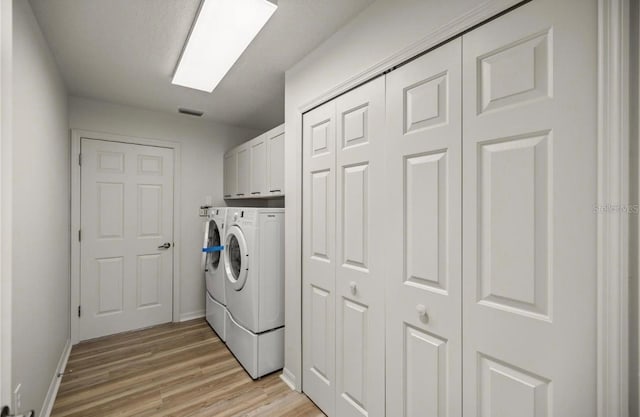 laundry room with cabinets, light wood-type flooring, and washer and clothes dryer