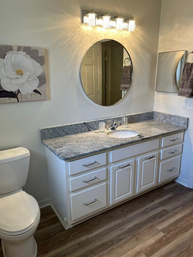 bathroom featuring wood-type flooring, vanity, and toilet